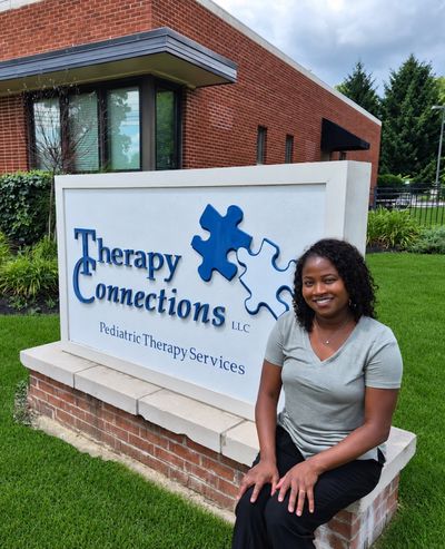 Owner Debbie Brooks smiling beside the Therapy Connections sign