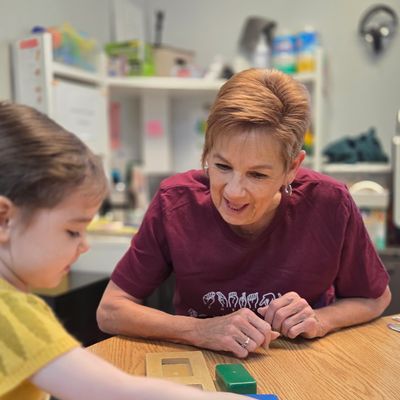 A speech therapist working with a young girl at a table